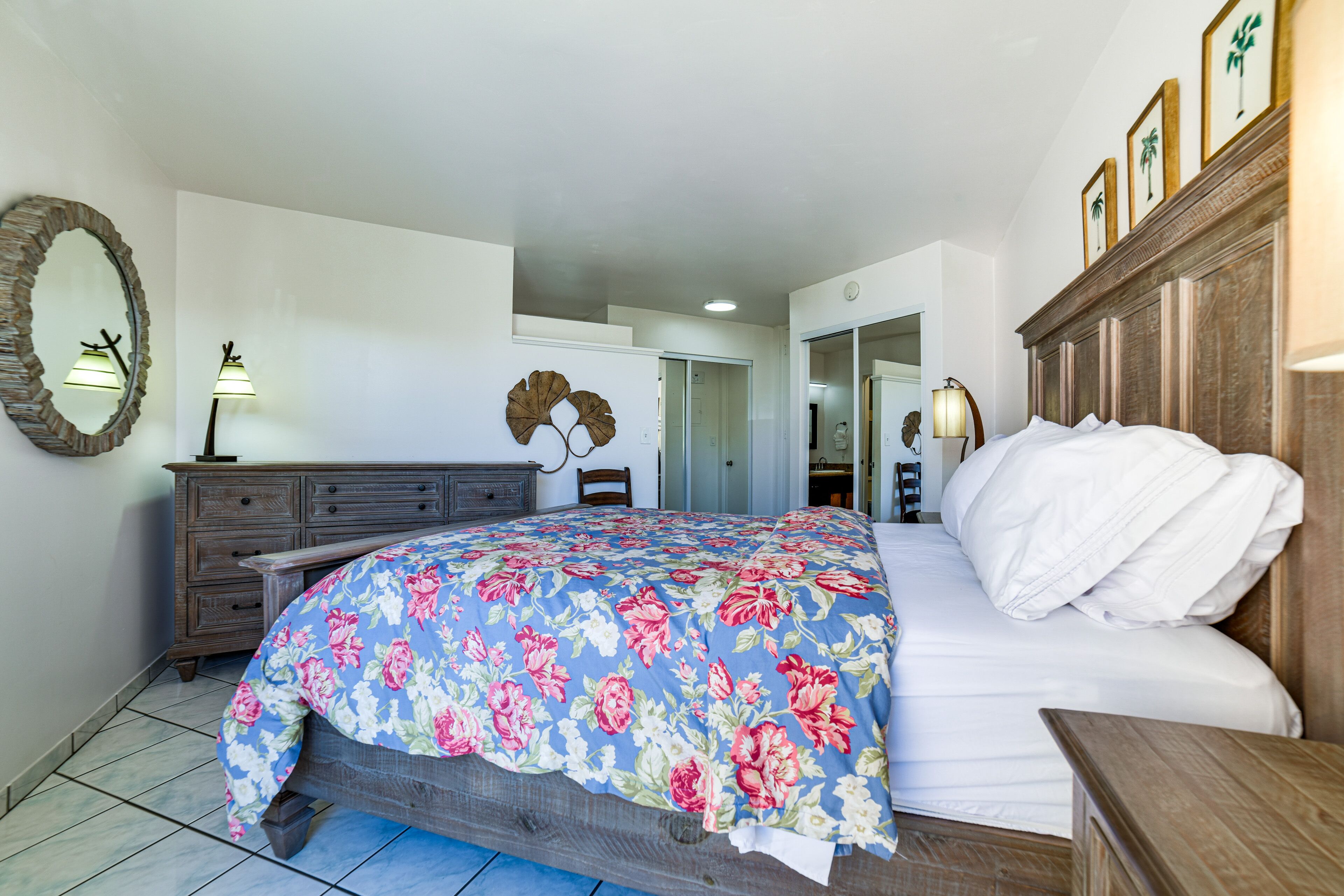A bedroom with a bed, dresser, and a mirror.