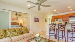 A living room with a sofa, a glass coffee table, and a ceiling fan.