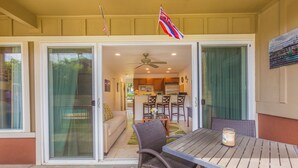 A covered patio area with a table and chairs, a sliding glass door leading to a kitchen, and an American flag.