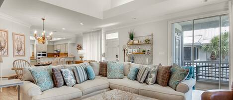 A spacious living room with a large sectional sofa, a wooden coffee table, and a view of the outside.