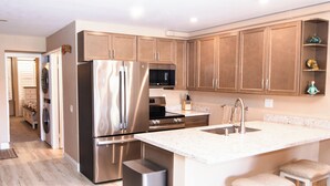 A modern kitchen with stainless steel appliances, wooden cabinets, and a marble countertop.