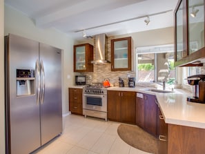 A modern kitchen with stainless steel appliances, wooden cabinets, a built-in oven, and a coffee maker.