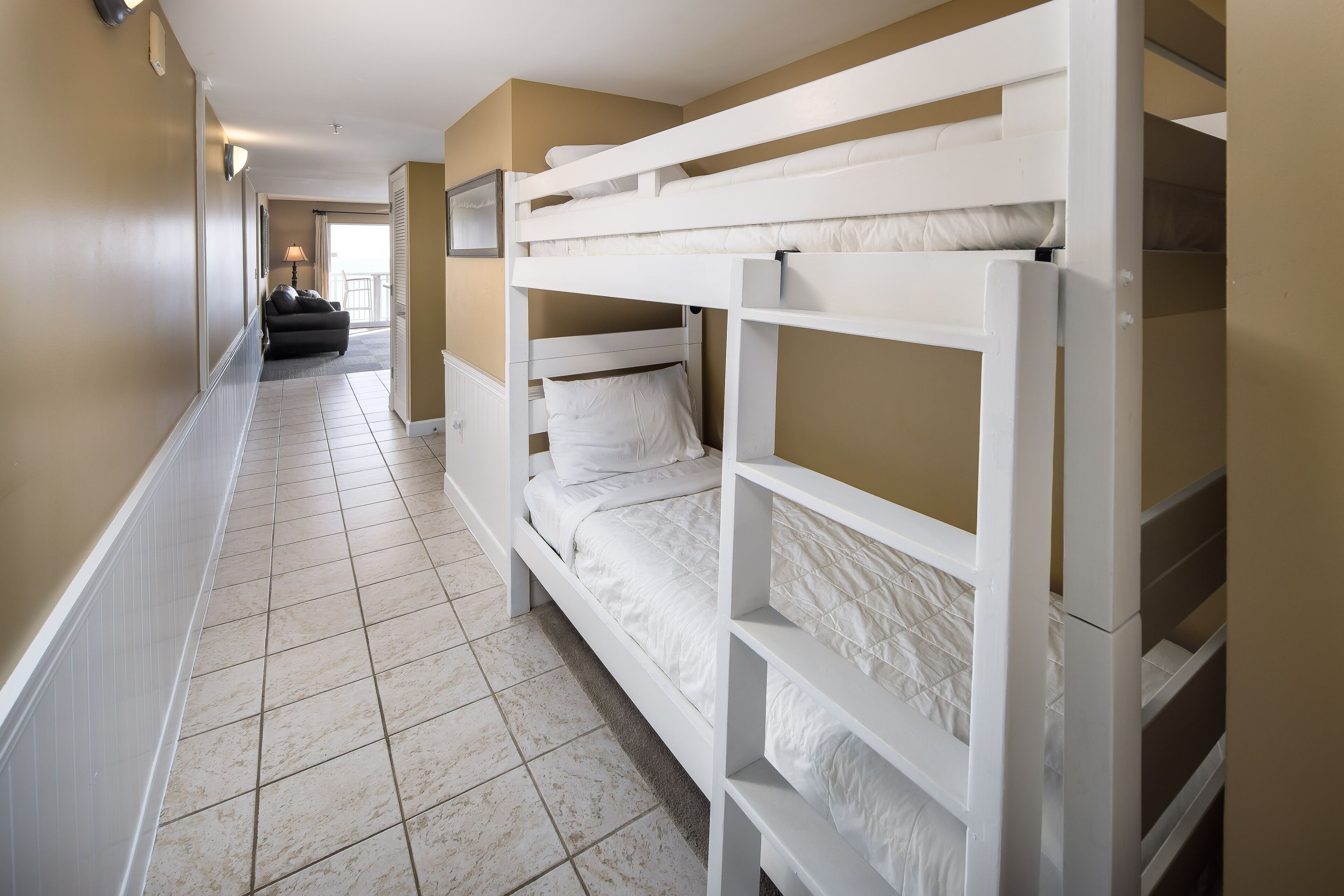 Habitación con literas y un pasillo que da a un balcón.