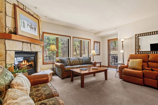 A living room with a fireplace, a sofa, a coffee table, and a leather armchair.