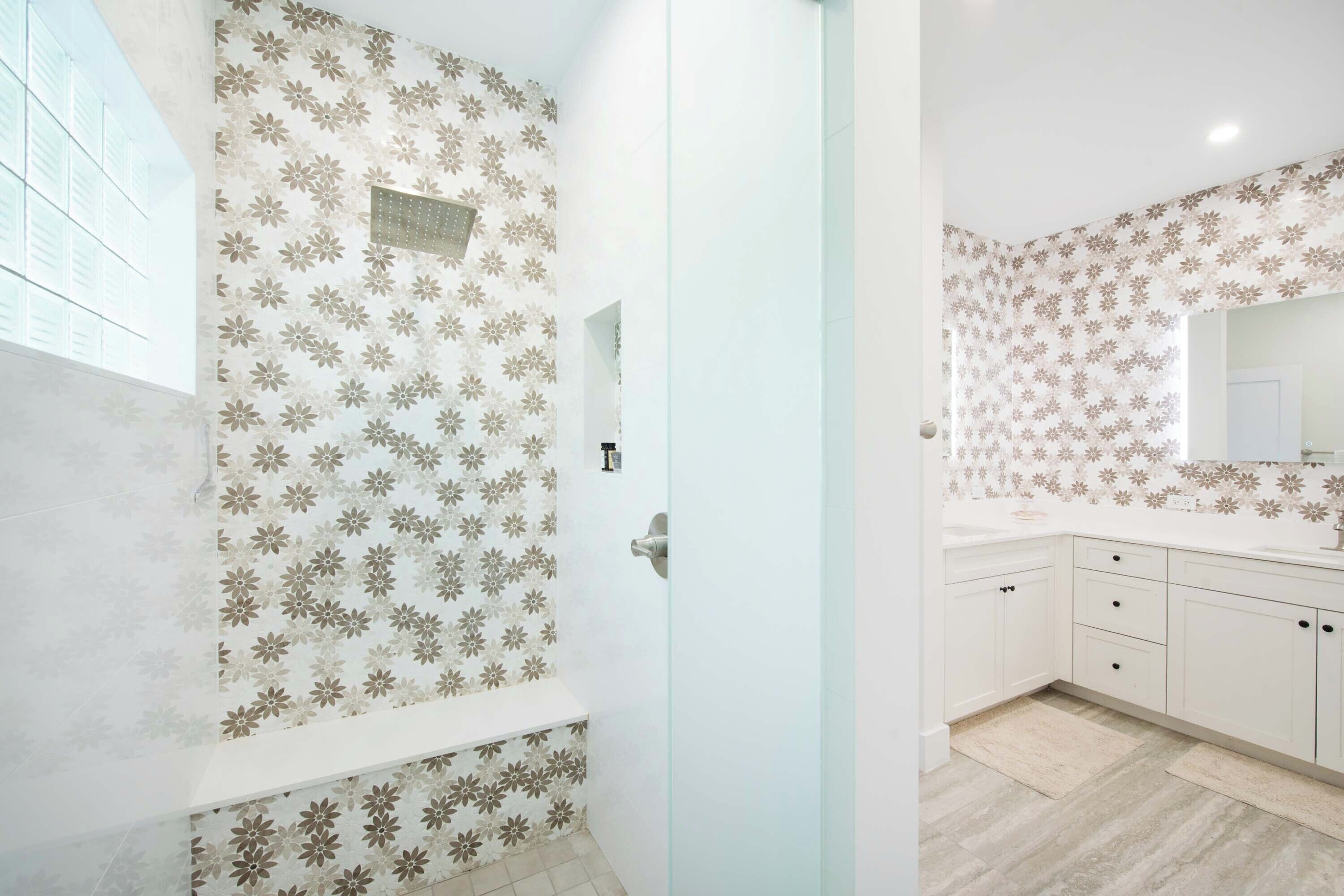 A bathroom with floral wallpaper, a shower area, and a sink with a mirror.
