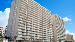 A high-rise hotel with multiple balconies, a flat roof, and a clear sky.