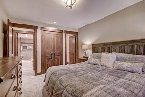 Une chambre à coucher avec un grand lit, une armoire en bois et une table de chevet avec une lampe.