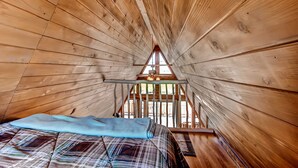A wooden cabin room with a bed, a window, and a ceiling fan. - Secluded & Cozy Antimony Cabin w/ Fire Pit (Antimony)