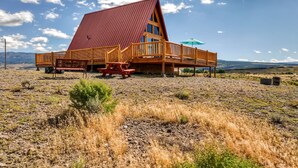 A wooden cabin with a red roof, a wooden deck, and a picnic table. - Secluded & Cozy Antimony Cabin w/ Fire Pit (Antimony)