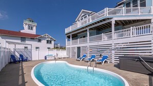 A pool area with blue chairs and a sign indicating no diving is allowed. - The Life of Riley - NH MP 10.5, Ocean View, 265 Yds to Beach, Pool, Hot Tub, Pool Table, Flex Stays (Nags Head)