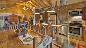 A rustic kitchen with wooden beams, a large dining table, and stainless steel appliances. - Beaver Creek Lodge: Stargazing Destination (Huntington)