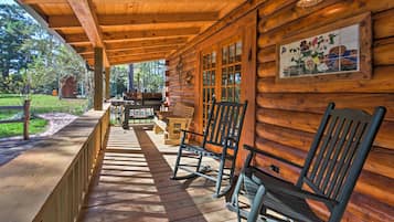 Une cabane en bois dotée d’une véranda, de fauteuils à bascule et d’une décoration murale en carreaux.