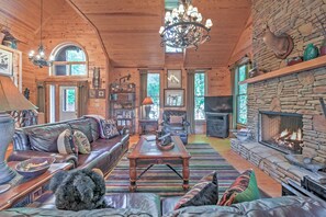 Un interior acogedor de cabaña de madera con chimenea de piedra, muebles de cuero y una araña.