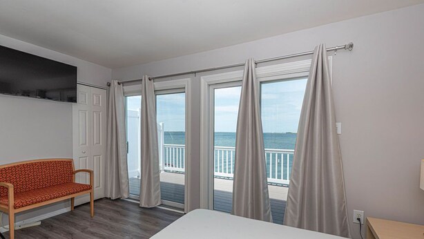 Ein Hotelzimmer mit Bett, einer Couch und großen Fenstern mit Vorhängen.