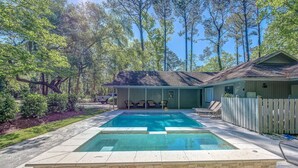 A rectangular swimming pool with a tiled deck, surrounded by a wooden fence and a house with a porch. - 20 Tupelo: Charming Sea Pines Home, Private Pool, Free Bikes (Hilton Head Island)