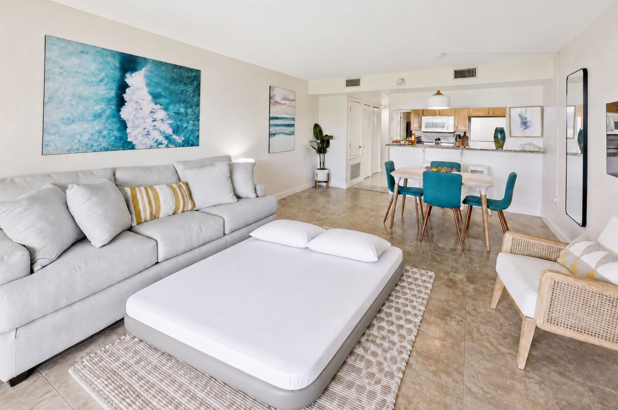 Un salon moderne avec un canapé, un grand lit et un coin repas avec des chaises.