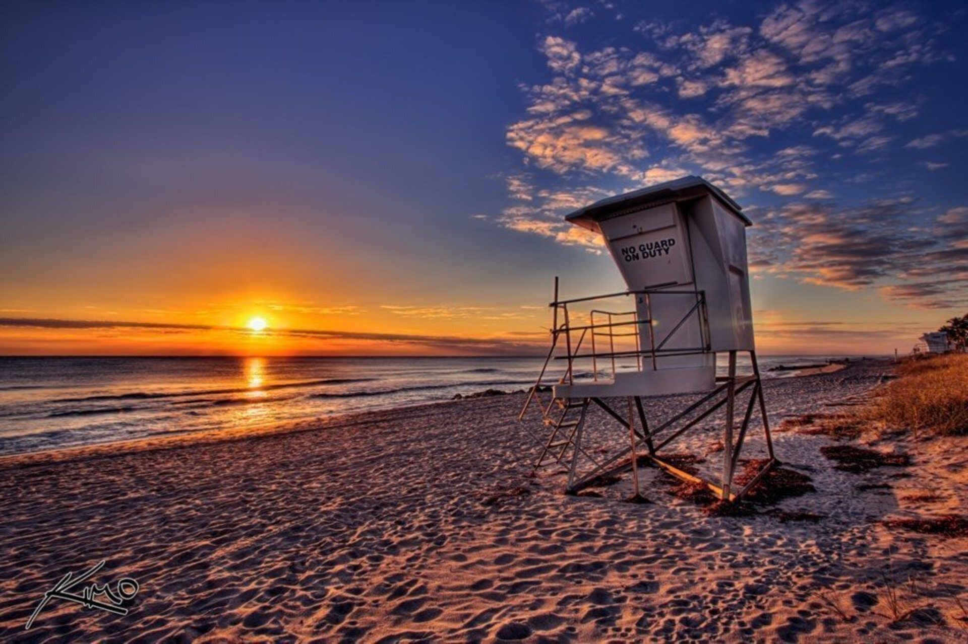 Una torre de salvavidas en una playa al atardecer.