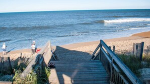 Une promenade en bois qui mène à une plage d’où l’on a une vue dégagée sur l’océan.