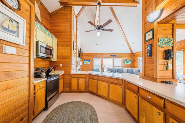 L’intérieur d’un chalet en bois comprend une cuisine, un coin repas et un ventilateur de plafond.