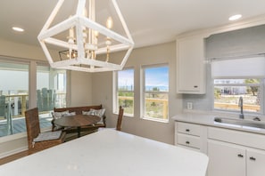 Une cuisine moderne avec des armoires blanches, un grand îlot central et une vue sur l’extérieur.