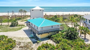 Una propiedad frente a la playa con un edificio de dos pisos, un tanque de agua separado y una playa arenosa.