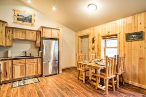 A kitchen with wooden cabinets, a stainless steel refrigerator, and a dining table with chairs.