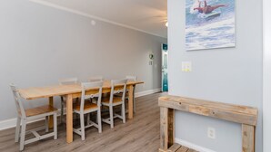 Ein Essbereich mit Holztisch und Stühlen, einer Bank und einem an der Wand befestigten Bild eines Surfers.