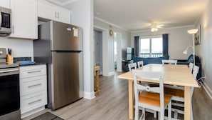 Eine moderne Küche mit weißen Schränken, einem Edelstahlkühlschrank und einem Essbereich mit einem Holztisch und Stühlen.