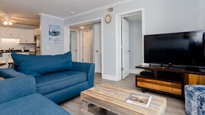 Ein modernes Wohnzimmer mit einem blauen Sofa, einem Holztisch und einem Flachbildfernseher.