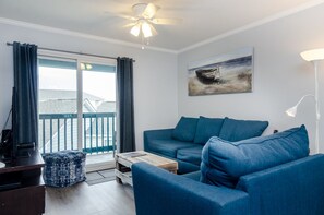 Relax in this stylish living room with a sofa, coffee table, and TV, plus a balcony with a view.