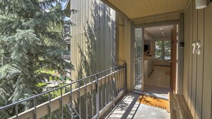 Ein Balkon mit Metallgeländer, der auf ein Gebäude und einen Baum blickt.