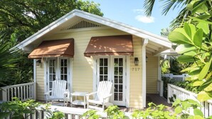 Ein Haus mit Veranda, zwei weiße Stühle und der Hausnummer 717 an der Wand.
