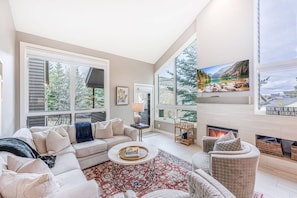 A spacious living room with a large window, a fireplace, and a cozy seating area.