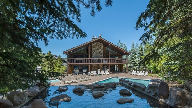 A lodge with a pool surrounded by rocks, a deck with lounge chairs, and a stone facade. - Canyons Resort Ski Home | Walk to Skiing + Free On Call Shuttle | 2 Fireplaces & 3 Cal-King Suites (Park City)