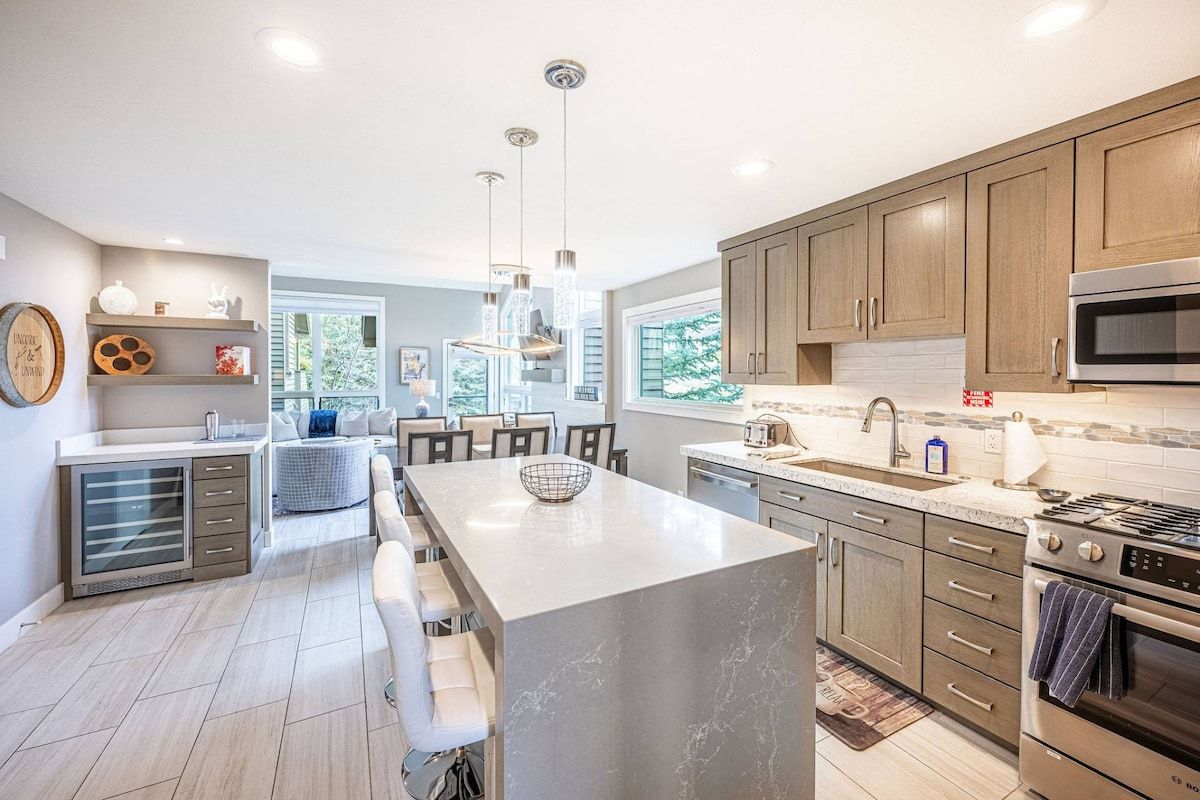 A modern kitchen with a central island, stainless steel appliances, and wooden cabinets.