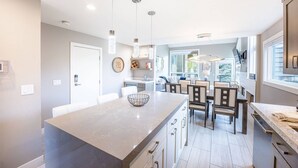 A modern kitchen with a central island, pendant lighting, and a view to the dining area. - Canyons Resort Ski Home | Walk to Skiing + Free On Call Shuttle | 2 Fireplaces & 3 Cal-King Suites (Park City)