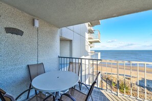 A balcony with a round table and chairs, a sign reading "Welcome to Cloud Nine", and a view of the beach and ocean. - Spacious, comfy 2 bedroom oceanfront condo with free WiFi, an outdoor pool, and a pretty ocean view located uptown just steps to the beach! (Ocean City)