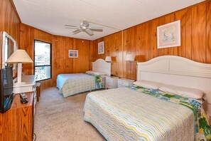A room with two beds, a ceiling fan, wooden walls, a TV, and a window. - Spacious, comfy 2 bedroom oceanfront condo with free WiFi, an outdoor pool, and a pretty ocean view located uptown just steps to the beach! (Ocean City)