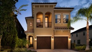 Une maison à deux étages avec un balcon, deux portes de garage et un jardin bien entretenu.
