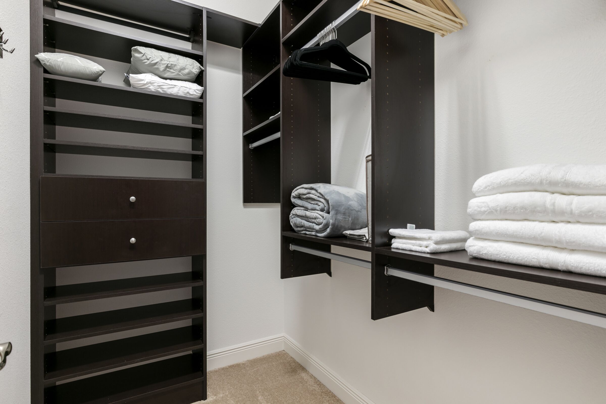 A walk-in closet with multiple shelves, a hanging rack, and a mirror.