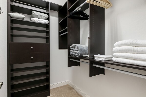 A walk-in closet with multiple shelves, a hanging rack, and a mirror.