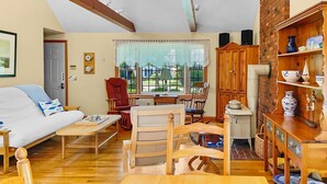 Ein gemütliches Wohnzimmer mit Holzboden, einer Couch, einem Esstisch und einer Küchenzeile mit Backsteinwand und Holzschränken.
