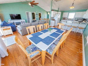 A spacious living room with a dining area, wooden flooring, and a ceiling fan.