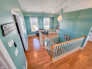 A multi-level home with a staircase, wooden floors, and teal walls.