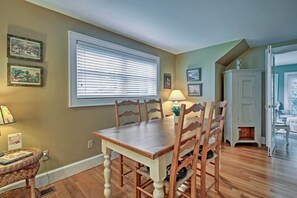 A dining area with a wooden table and chairs, a window with blinds, and wall-mounted pictures. - 1/2 Mi to Beach: Lovely Guesthouse in Kennebunk! (Kennebunk)