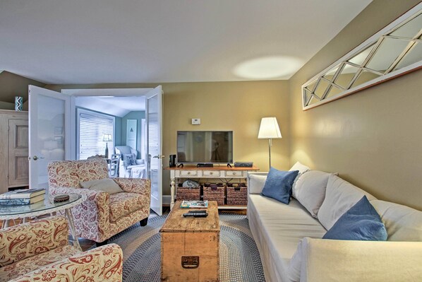 A living room with a sofa, armchair, coffee table, and a television. - 1/2 Mi to Beach: Lovely Guesthouse in Kennebunk! (Kennebunk)