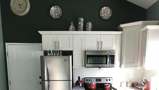 A modern kitchen with white cabinets, a stainless steel refrigerator, a microwave, and a stove. - Sleep Easy, Relax In Comfort (Caymanas Estates)