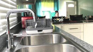 A kitchen with a stainless steel sink, a built-in oven, and a ceiling fan. - Sleep Easy, Relax In Comfort (Caymanas Estates)