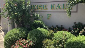 A sign for "ROSE HALL F" with surrounding greenery and a clear sky. - Sleep Easy, Relax In Comfort (Caymanas Estates)