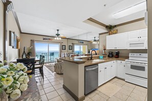 A kitchen with a central island, white cabinets, a dishwasher, and a view to the outside.